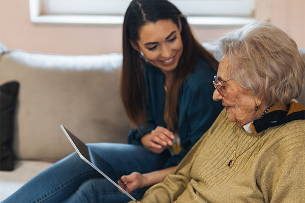 Younger woman helping elderly woman with tablet